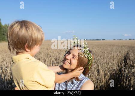 mamma e figlio felici in un campo di grano, il ragazzo tiene delicatamente la testa delle madri. concetto di amore parentale, maternità. Festa della mamma. goditi la natura e la vita, f Foto Stock