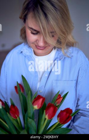 una donna di medie dimensioni ha in mano un mazzo di tulipani rossi Foto Stock