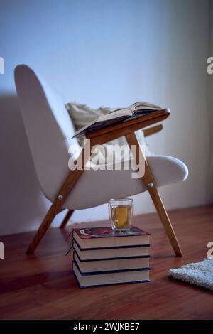 luogo perfetto per leggere e rilassarsi, una poltrona bianca circondata da libri in una sala luminosa Foto Stock