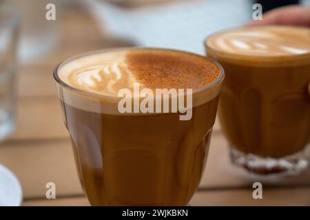 Primo piano di due tazze di latte con schiuma posizionata su un tavolo Foto Stock
