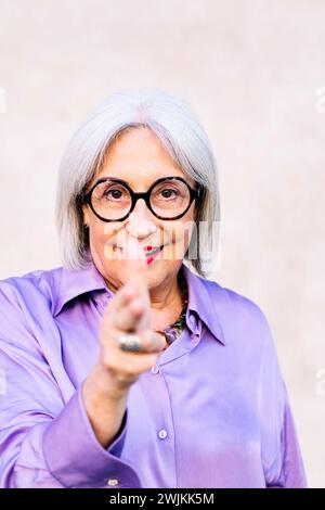 donna anziana che punta con le dita come una pistola Foto Stock