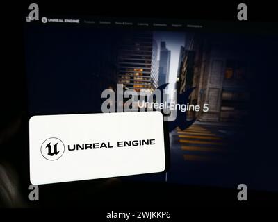 Persona con smartphone con logo del software di gioco 3D Unreal Engine (Epic Games) davanti al sito Web. Mettere a fuoco il display del telefono. Foto Stock