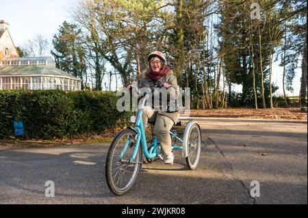 Tienen, Fiandre, Belgio, 28 gennaio 2024 - donna felice con la sindrome di Down alla guida di un triciclo Foto Stock