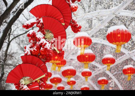 Decorazioni del capodanno cinese nella città invernale. Vicolo festivo decorato con ventilatori di carta rossa e lanterne Foto Stock