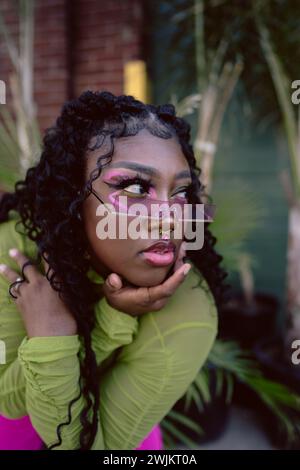 Primo piano di una giovane donna nera che posa con occhiali da sole colorati Foto Stock