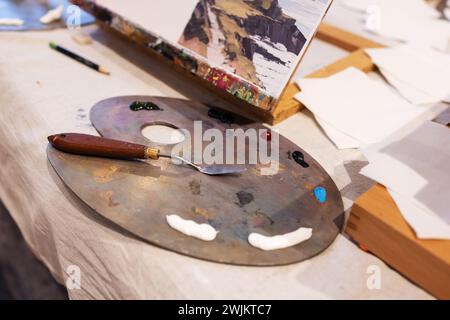 Tavolozza con vernici ad olio, coltello per tavolozza sul tavolo Foto Stock