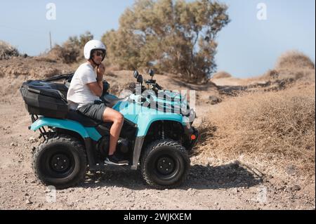 Giovane che si assicura il casco su un atv a quattro ruote su pista fuoristrada Foto Stock