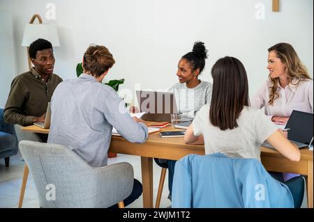 I colleghi si sono riuniti in ufficio mentre lavoravano sui notebook Foto Stock