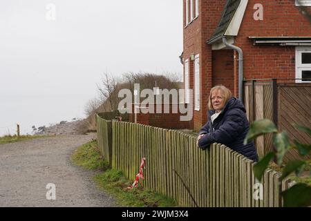 PRODUZIONE - 14 febbraio 2024, Schleswig-Holstein, Lübeck-Travemünde: Renate Paulien-Wittmaack, presidente distrettuale dell'organizzazione giovanile "SJD - Die Falken" si trova di fronte al centro giovanile "Haus Seeblick" nel distretto di Brodten sul Mar Baltico. Il centro giovanile "Haus Seeblick", situato direttamente sulle scogliere di Brodten, è chiuso per bambini e giovani dopo un'altra demolizione. Solo quattro metri si trovano tra un angolo della 'Haus Seeblick' e l'abisso. Alla fine di gennaio, un albero cadde lungo il bordo e lasciò un buco nel sentiero di fronte alla casa. Foto: Marc Foto Stock