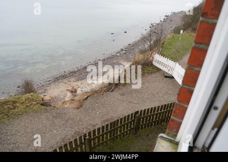 PRODUZIONE - 14 febbraio 2024, Schleswig-Holstein, Lübeck-Travemünde: Vista da una finestra al secondo piano del centro giovanile "Haus Seeblick" dell'organizzazione giovanile "SJD - Die Falken" sul bordo della scogliera nel distretto di Brodten sul Mar Baltico. Il centro giovanile "Haus Seeblick", che si trova direttamente sulle scogliere di Brodten, è ora chiuso per i bambini e il lavoro giovanile dopo il crollo di un'altra scogliera. Solo quattro metri si trovano tra un angolo della 'Haus Seeblick' e l'abisso. Alla fine di gennaio, un albero cadde lungo il bordo e lasciò un buco nel sentiero di fronte Foto Stock