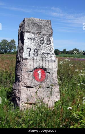 Antica pietra miliare fatta di granito dall'autostrada 110 (precedentemente numero 1) a Kitula, Finlandia, con paesaggio estivo. Foto Stock