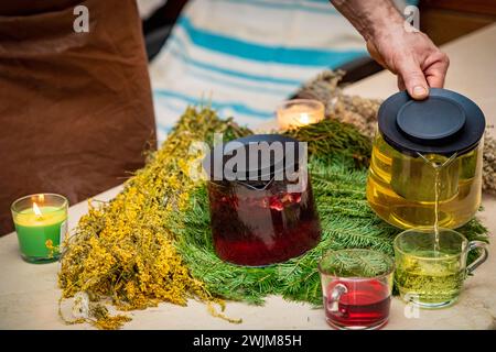 Utilizzando una teiera, qualcuno sta versando un liquido caldo e fumante in una tazza sulla stoviglie erbosa. Potrebbe essere tè, una bevanda alcolica, o una soluzione per Foto Stock