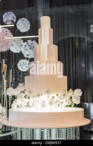 Una torta nuziale decorata con fiori sul tavolo Foto Stock