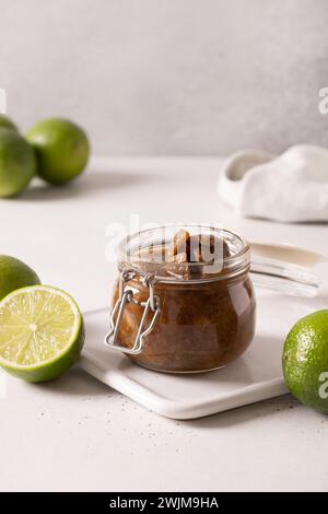 Popolare sottaceti di lime dello Sri Lanka con sale, peperoncino, pepe in vaso di vetro su sfondo grigio. Formato verticale. Foto Stock