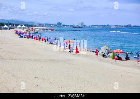 Gangneung City, Corea del Sud - 29 luglio 2019: Una vivace scena alla spiaggia di Yeongjin, con barche nel Mare Orientale, ombrelloni colorati nella sabbia, e. Foto Stock