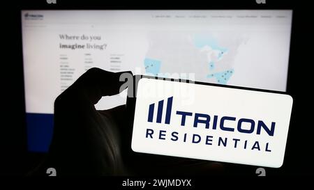 Persona che possiede uno smartphone con il logo della società immobiliare canadese Tricon Residential Inc. Davanti al sito Web. Mettere a fuoco il display del telefono. Foto Stock