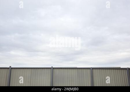 Recinzione in acciaio ondulato contro il cielo blu. Superficie in metallo ondulato o acciaio galvanizzato Foto Stock