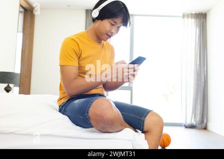 Adolescente asiatico ama la musica sul suo telefono a casa, con spazio di copia Foto Stock