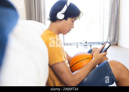 Adolescente asiatico ama la musica con le cuffie a casa, con spazio di copia Foto Stock