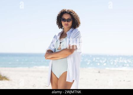 La giovane donna birazziale sta in piedi con fiducia sulla spiaggia Foto Stock