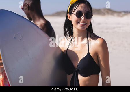 La giovane donna birazziale e l'uomo afroamericano si godono la spiaggia Foto Stock