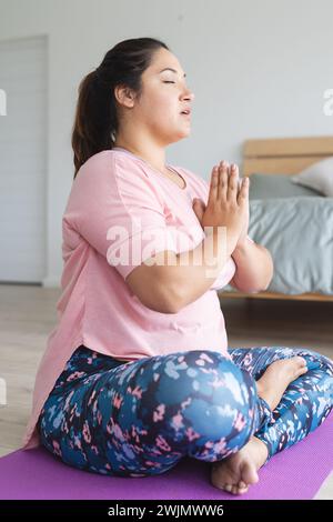 Giovane donna birazziale più grande pratica yoga a casa Foto Stock