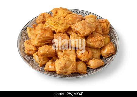 Piatto con biscotti al miele Rghayef fritti in profondità, a forma quadrata, da vicino isolati su sfondo bianco Foto Stock