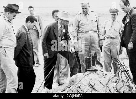 J. Robert Oppenheimer (in cappello di colore chiaro), il generale Leslie Groves (grande uomo in abito militare alla sinistra di Oppenheimer), e altri nel sito Ground zero del test Trinity dopo i bombardamenti di Hiroshima e Nagasaki, New Mexico 1945. Foto Stock