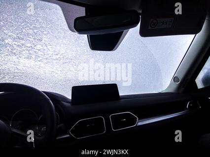 Parabrezza coperto di ghiaccio visto dall'interno della vettura. Guida sicura durante l'inverno Foto Stock