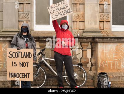 Due manifestanti di Black Lives Matter stanno di fronte a una bicicletta indossando giacche con cappuccio e maschere che tengono cartelli che leggono la Scozia non è innocente e ed Foto Stock
