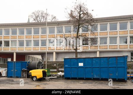 Contenitori blu metallizzati, un generatore elettrico giallo e una bobina con cavo vicino all'edificio amministrativo. Foto Stock