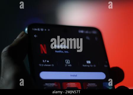 Una mano di un uomo tiene un cellulare con il logo Netflix sullo schermo del cellulare. schermata di messa a fuoco selettiva dell'app appstore. Editoriale illustrativo Foto Stock