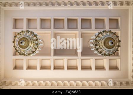 Grande lampadario vintage vintage con lampadine a lume di candela appese a un soffitto in legno. Telaio in metallo con decorazioni forgiate. Foto Stock