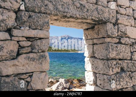 Porta di un'antica casa in pietra sulla spiaggia idilliaca dell'isola di Vrnik vicino a Korcula, Croazia. Vista del bellissimo mare e della penisola di Peljesac sul retro. Foto Stock