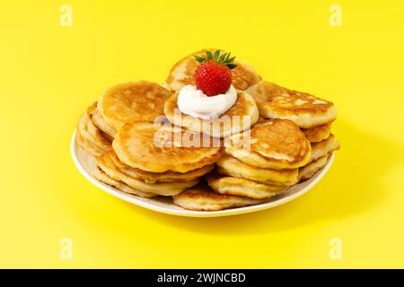 Mini pancake con fragole e panna acida su sfondo giallo Foto Stock