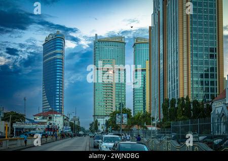 Il traffico percorre Sokoine Drive al crepuscolo lontano dai moderni e alti edifici nel quartiere finanziario centrale di Ilala a Dar es Salaam, Tanzania Foto Stock