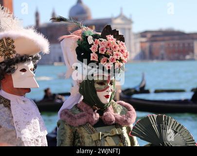 Venezia, VE, Italia - 13 febbraio 2024: Due persone travestite da maschere e abiti storici in riva al mare Foto Stock