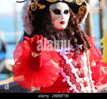 Venezia, VE, Italia - 13 febbraio 2024: Donna elegante in maschera con parrucca e guanti rossi Foto Stock