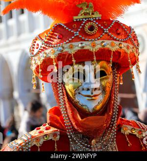 Venezia, VE, Italia - 13 febbraio 2024: Maschera d'oro e grande cappello rosso durante il Carnevale Foto Stock
