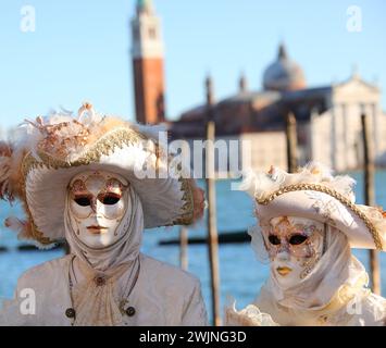 Venezia, VE, Italia - 13 febbraio 2024: Uomo e donna mascherati con abiti fatti a mano durante il carnevale in riva al mare Foto Stock