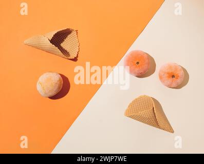 Coni di gelato con frutta estiva congelata su sfondo arancio e beige. Concetto gastronomico estivo minimalista. Posizione piatta. Foto Stock