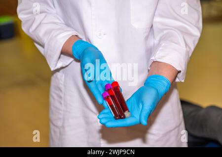 Medico irriconoscibile con guanti blu che raccoglie campioni di sangue e li tiene in un centro di donazione Foto Stock