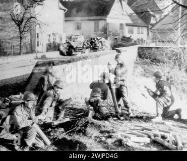 Seventh Army Yanks Shell Germany -- Un equipaggio di mortai del Settimo esercito americano pompa proiettili in Germania da una posizione appena fuori dalla strada principale della città di confine ALSAZIANO-tedesca di LAUTERBIURG.da sinistra a destra sono: PFC EUGEN GILES, ITHACA, N.Y.; Pvt. JOSEPH BARTANUS, AVELLA, PA.; CPL GEORGE CARLISLE, HENDERSON, N.C.; PA.DICEMBRE 27, 1944. (Foto di AP Wirephoto). Foto Stock