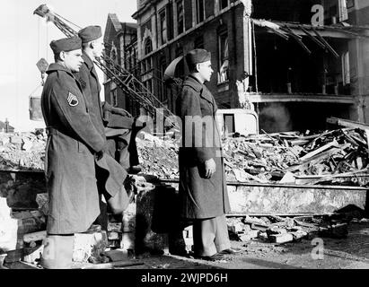 I soldati americani visitano Bombed School -- da sinistra a destra:- Sergt. E. Yelle, di Courtland, New York, Sergt. A. Tucker, dell'Alabama e Cpl. M. Perkins, di Tracey, California, che guarda le squadre di soccorso al lavoro alla scuola di Londra bombardata. Nove bambini erano noti per giacere ancora schiacciati sotto il relitto quasi certamente morti. Quarantasette già estratte dai detriti attesi per la sepoltura. Altri sessantadue sono rimasti in ospedale, gravemente feriti. L'età di tutti era compresa tra i cinque e i quattordici anni. 22 gennaio 1943. Foto Stock