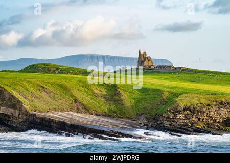 Famoso castello di Classiebawn nel pittoresco paesaggio di Mullaghmore Head. Spettacolare vista del tramonto con enormi onde che si infrangono a terra. Punto di firma di Wil Foto Stock