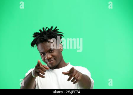 Un uomo, primo piano, su uno sfondo verde, punta in avanti. Foto Stock