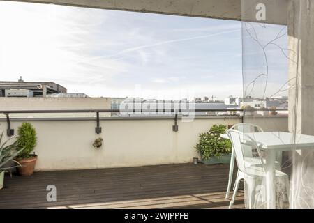 Un grazioso tavolo da giardino in metallo blu pastello con sedie abbinate su una terrazza urbana con pavimenti in legno che si affacciano su altri edifici della città Foto Stock