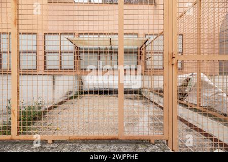 Alcuni cubicoli divisi da recinzioni metalliche dipingevano un chiaro colore terracotta Foto Stock