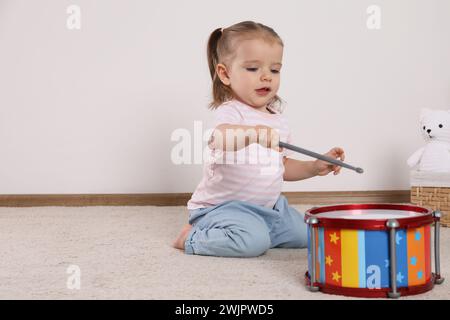 Una bambina carina che suona con la batteria e le bacchette a casa, spazio per il testo Foto Stock