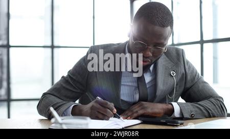 Un uomo d'affari in un primo piano in una giacca, scrive e controlla i documenti in ufficio Foto Stock